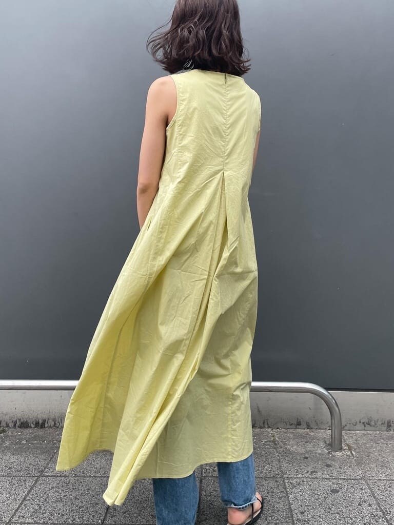 ホワイト系のハンドバッグ、ブルー系のデニムパンツ、グリーン系のワンピースを着用したレディースの春コーディネートの4枚目の写真