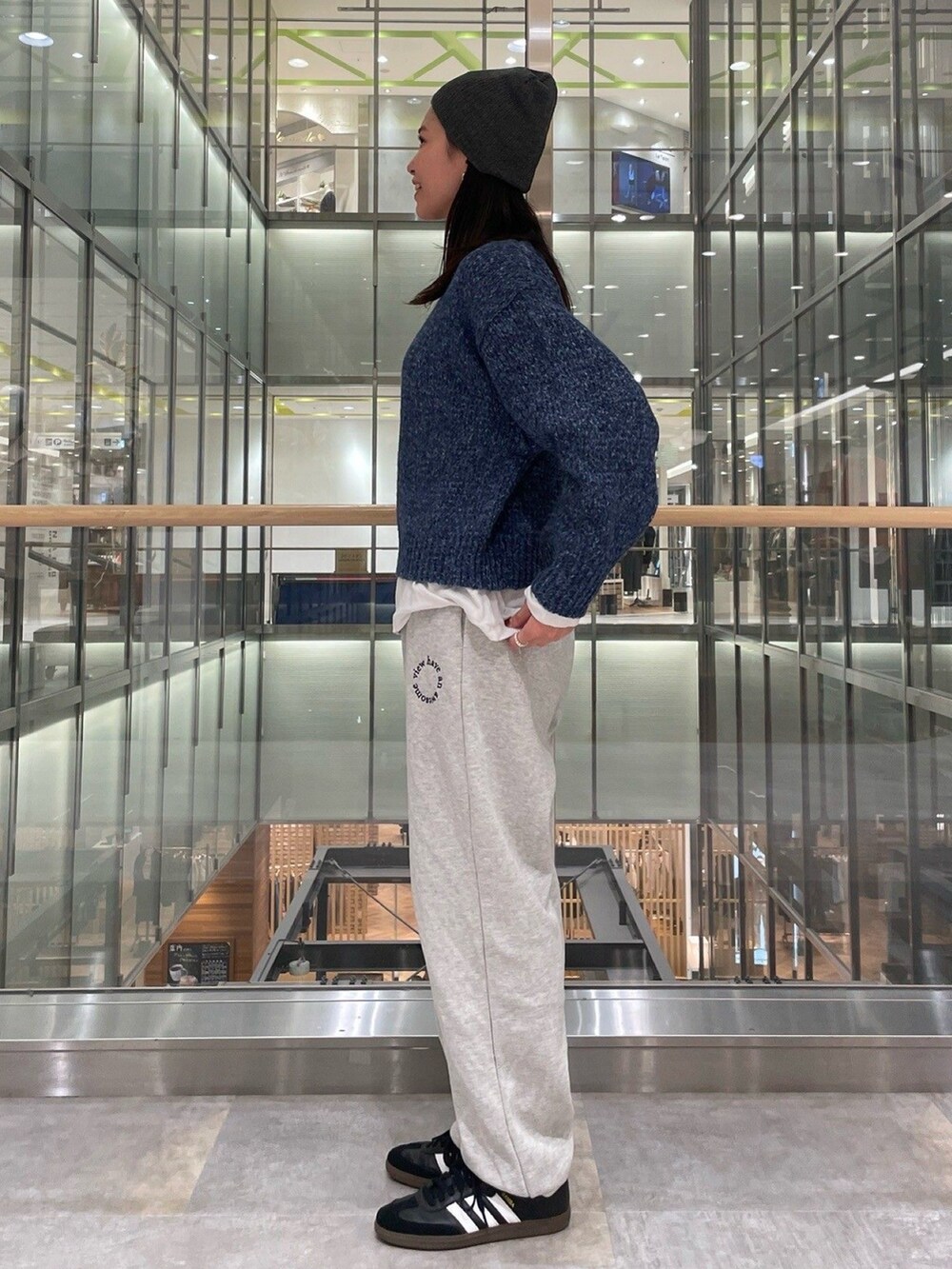 ブルー系のニット/セーター、ホワイト系のTシャツ/カットソー、グレー系のスウェットパンツを着用したレディースの秋コーディネートの2枚目の写真