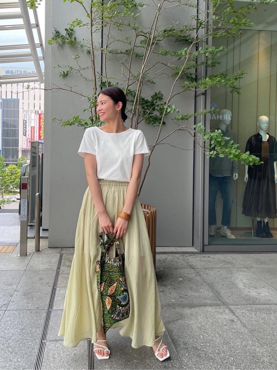 グリーン系のショルダーバッグ、ホワイト系のTシャツ/カットソー、グリーン系のスカートを着用したレディースの春コーディネートの2枚目の写真