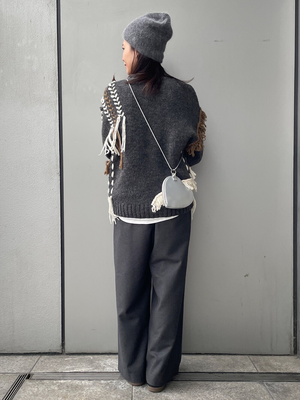グレー系のニット/セーター、ホワイト系のTシャツ/カットソー、グレー系のその他パンツを着用したレディースの冬コーディネートの3枚目の写真