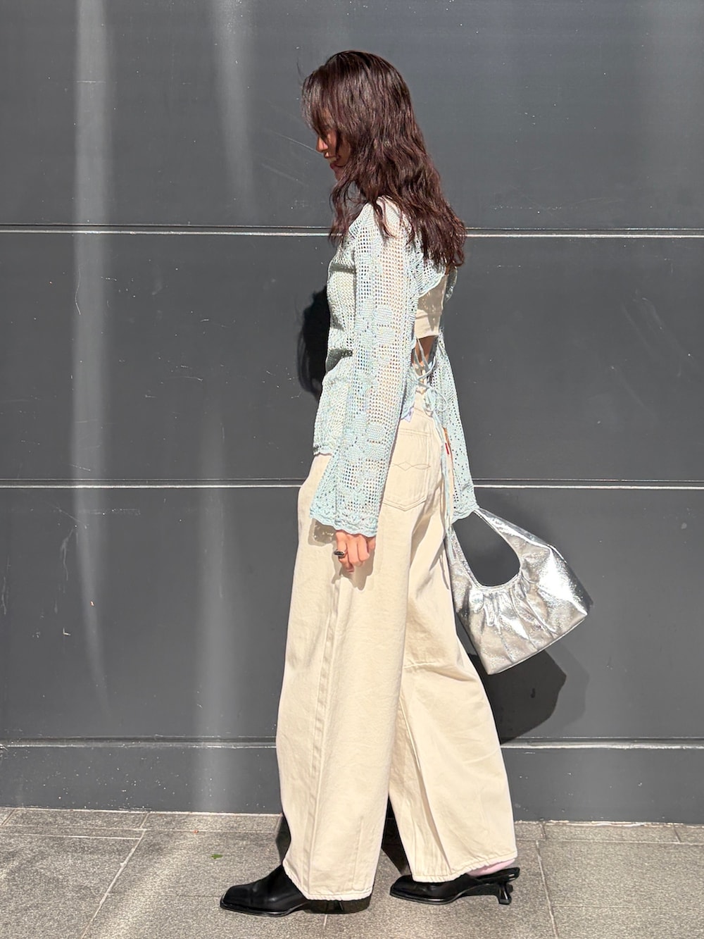 ブルー系のニット/セーター、ホワイト系のデニムパンツ、シルバー系のハンドバッグを着用したレディースの春コーディネートの3枚目の写真