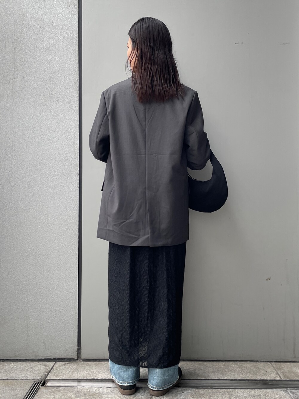 グレー系のテーラードジャケット、ブラック系のワンピース、ブルー系のデニムパンツを着用したレディースの秋コーディネートの2枚目の写真