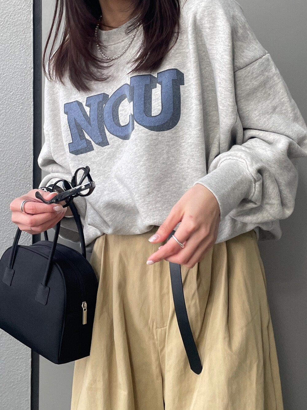 グレー系のスウェット、ベージュ系のチノパンツ、ブラック系のボストンバッグを着用したレディースの冬コーディネートの5枚目の写真