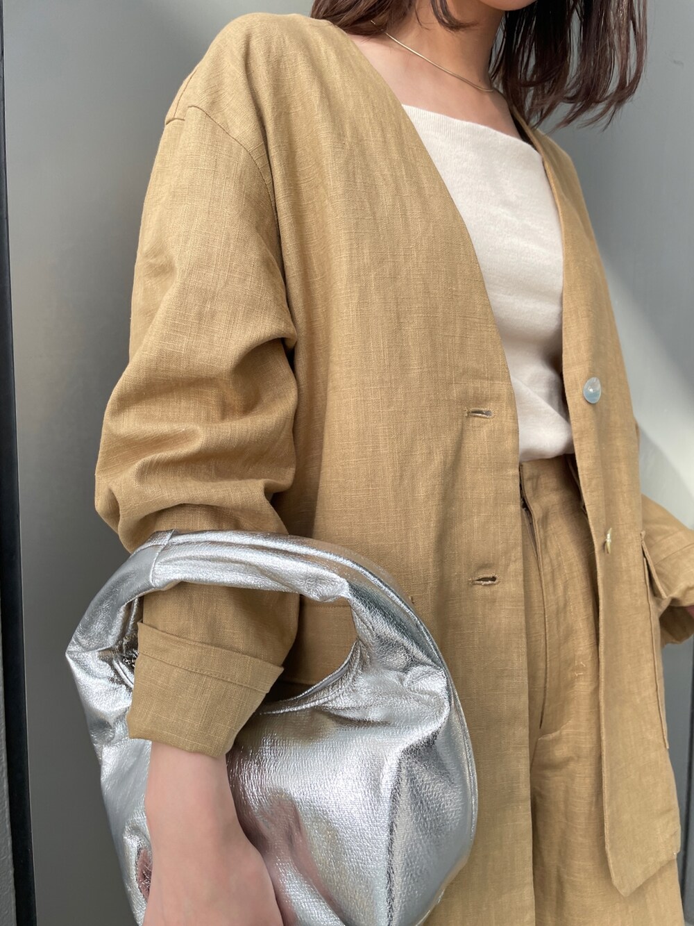 ベージュ系のテーラードジャケット、ベージュ系のその他パンツ、ホワイト系のキャミソールを着用したレディースの春コーディネートの3枚目の写真