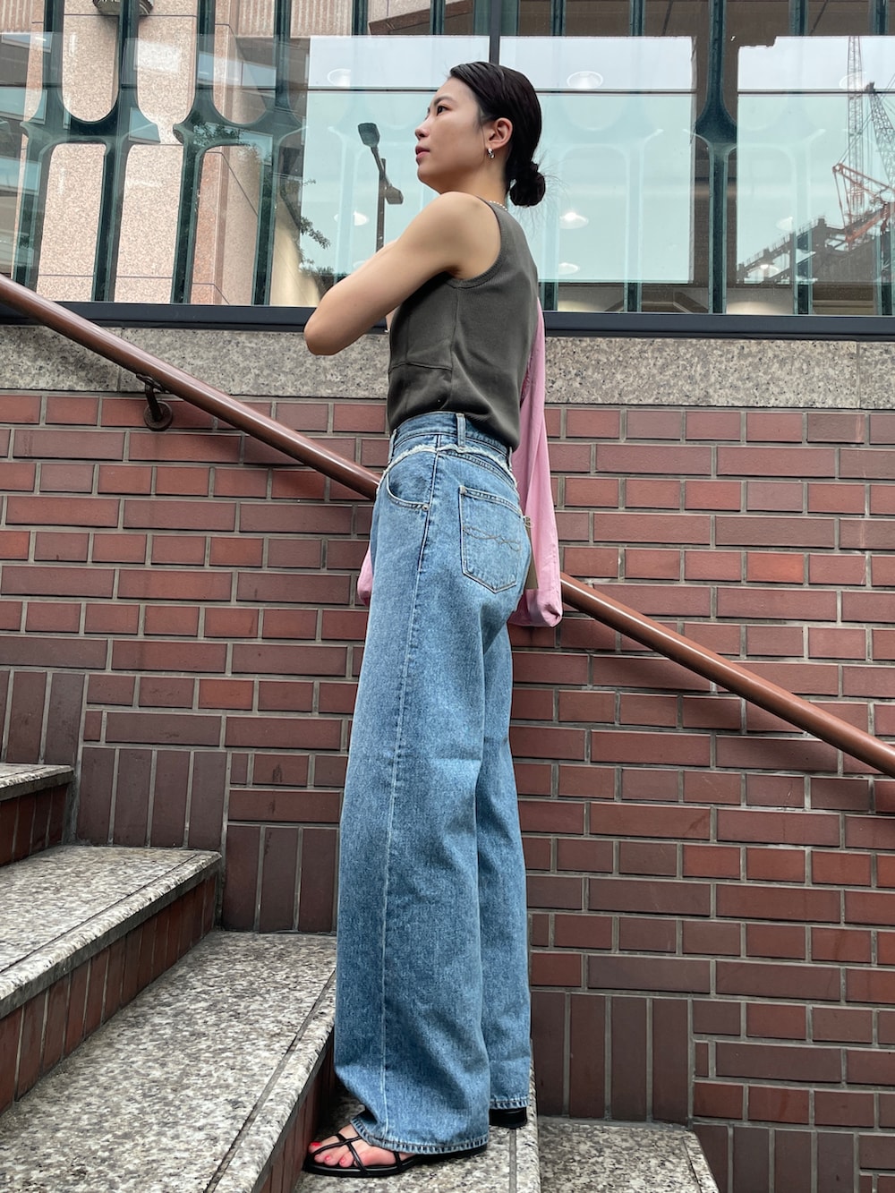 ピンク系のトートバッグ、ブルー系のデニムパンツ、グレー系のタンクトップを着用したレディースの夏コーディネートの2枚目の写真
