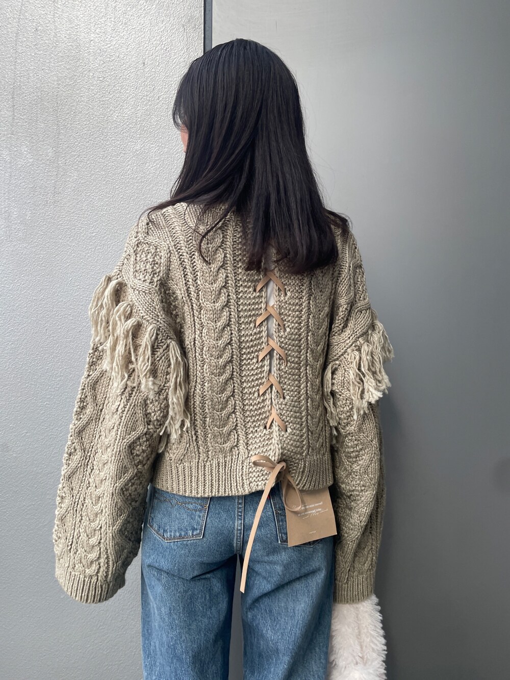 ブルー系のデニムパンツ、ブラウン系のニット/セーター、ホワイト系のハンドバッグを着用したレディースの冬コーディネートの5枚目の写真