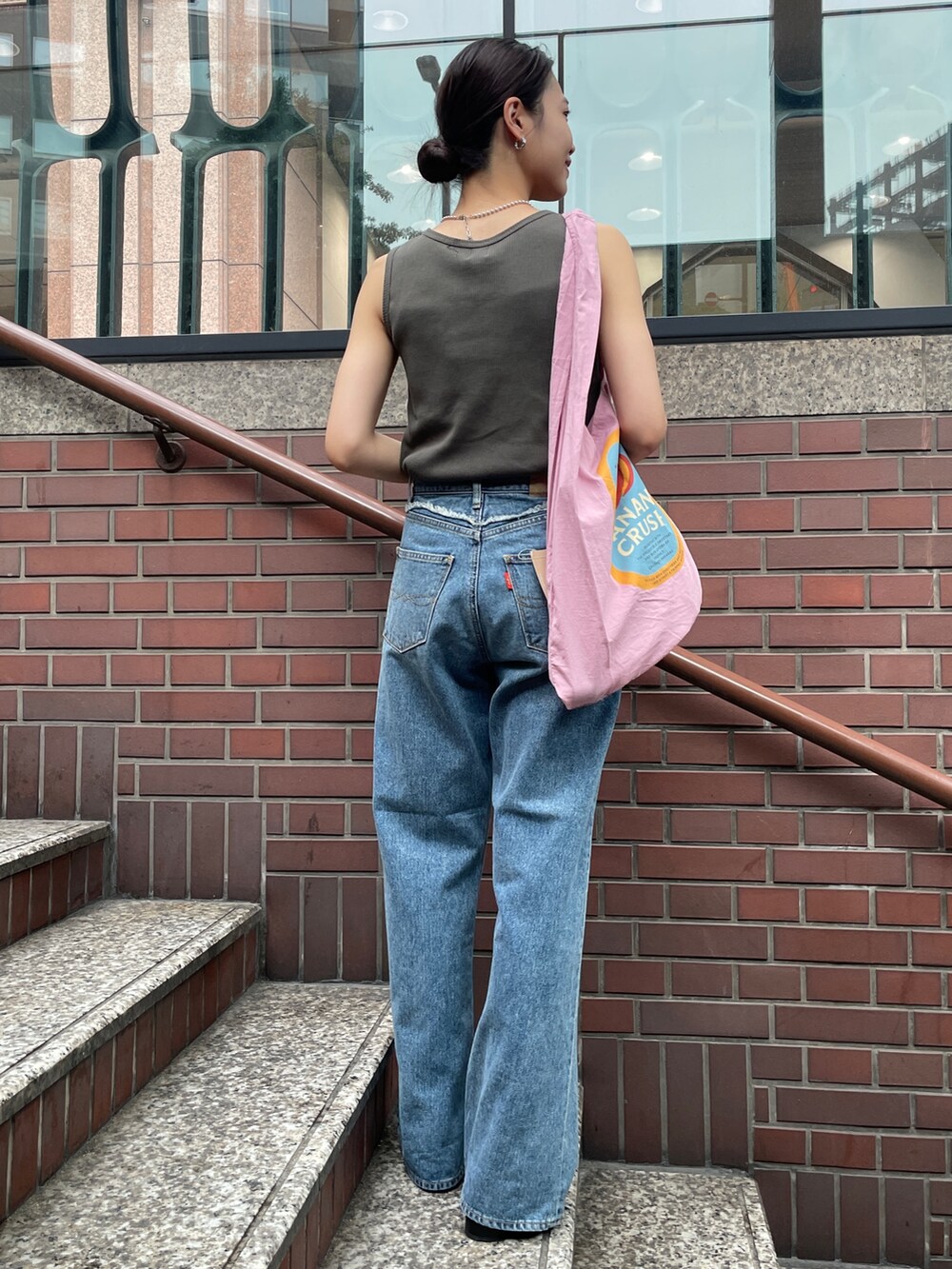 ピンク系のトートバッグ、ブルー系のデニムパンツ、グレー系のタンクトップを着用したレディースの夏コーディネートの3枚目の写真