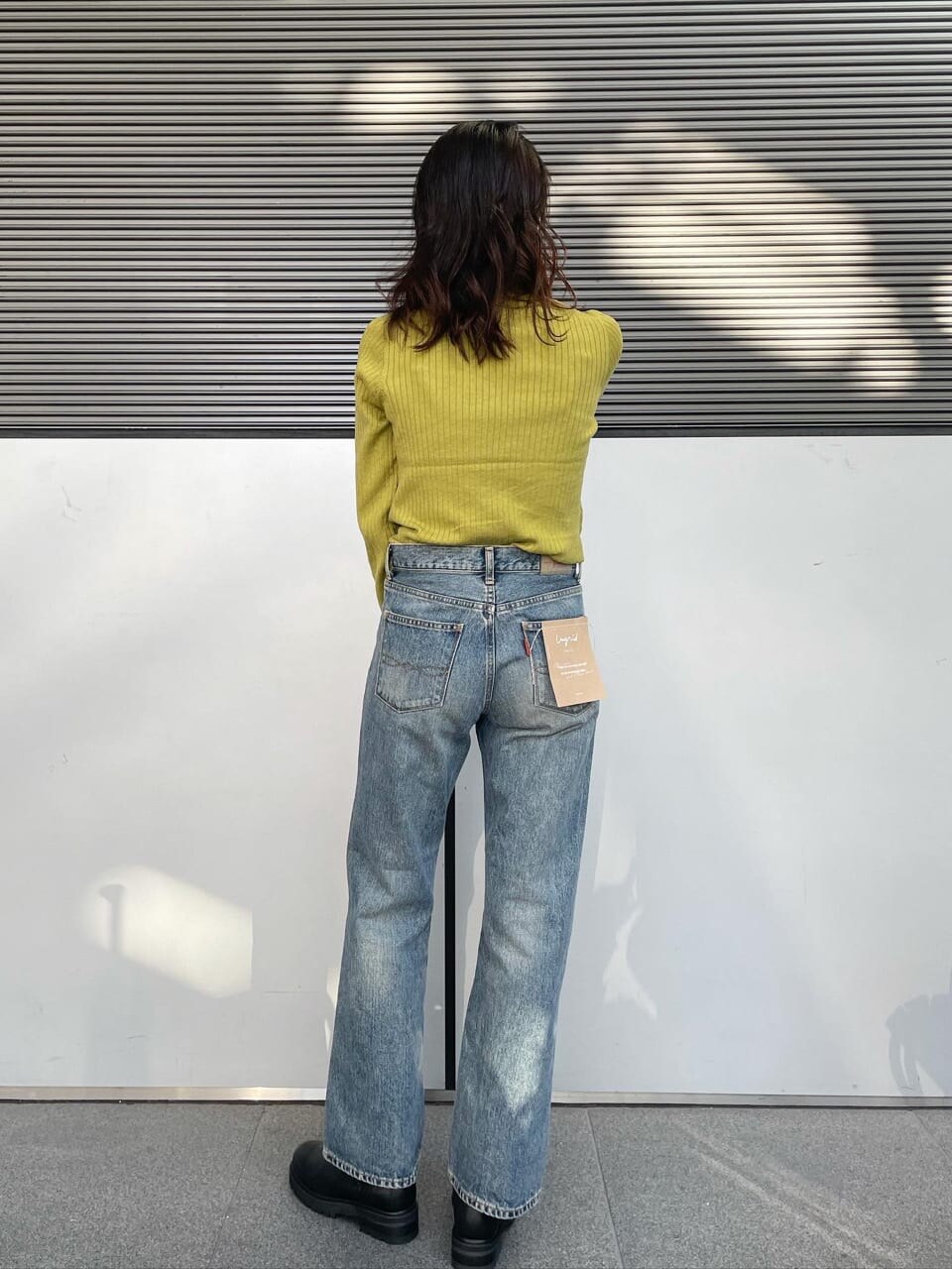 ブラウン系のステンカラーコート、ブルー系のデニムパンツ、グリーン系のニット/セーターを着用したレディースの秋コーディネートの2枚目の写真
