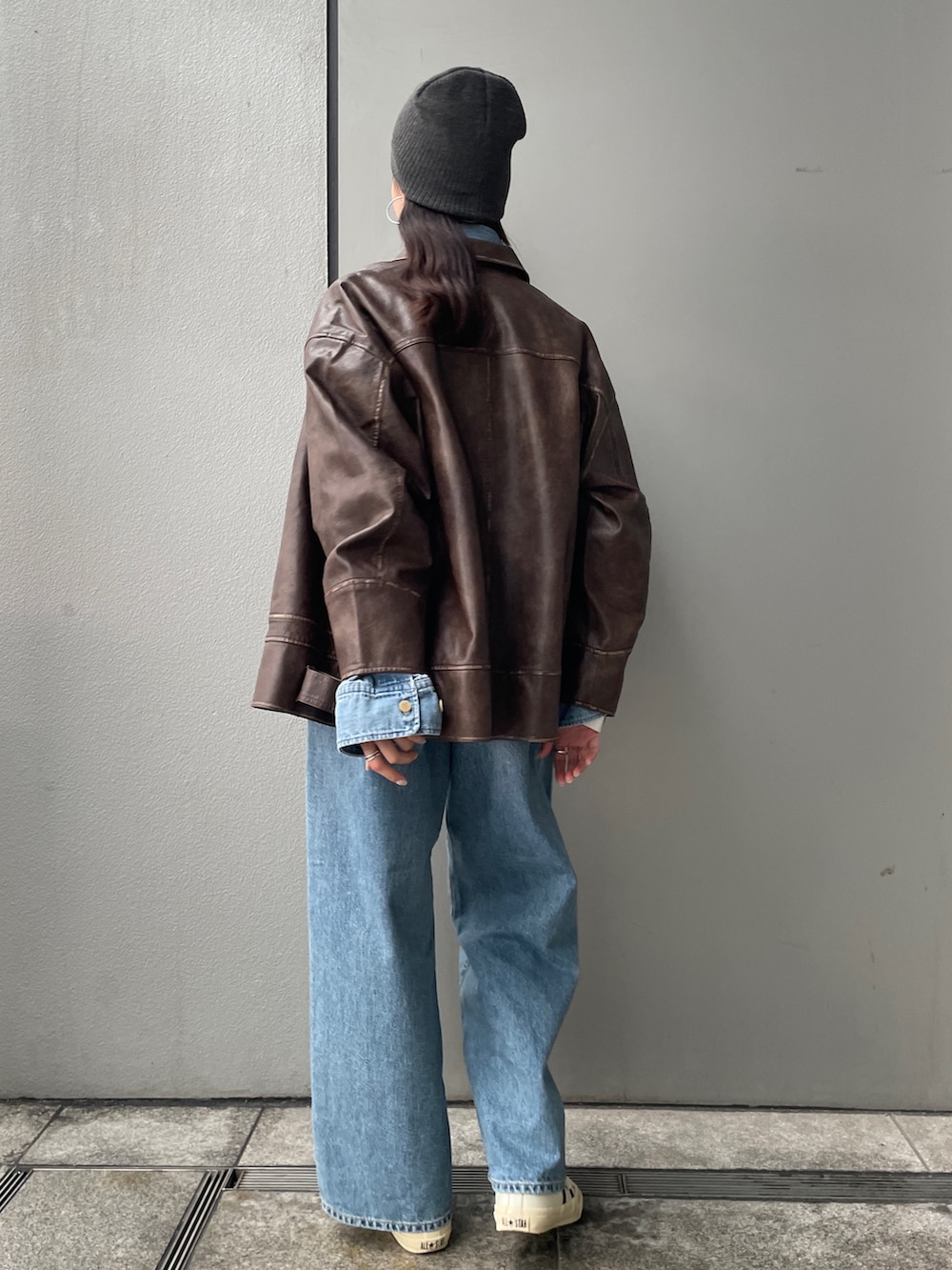 ブラウン系のブルゾン、ホワイト系のエコバッグ/サブバッグ、ブルー系のデニムパンツを着用したレディースの冬コーディネートの2枚目の写真