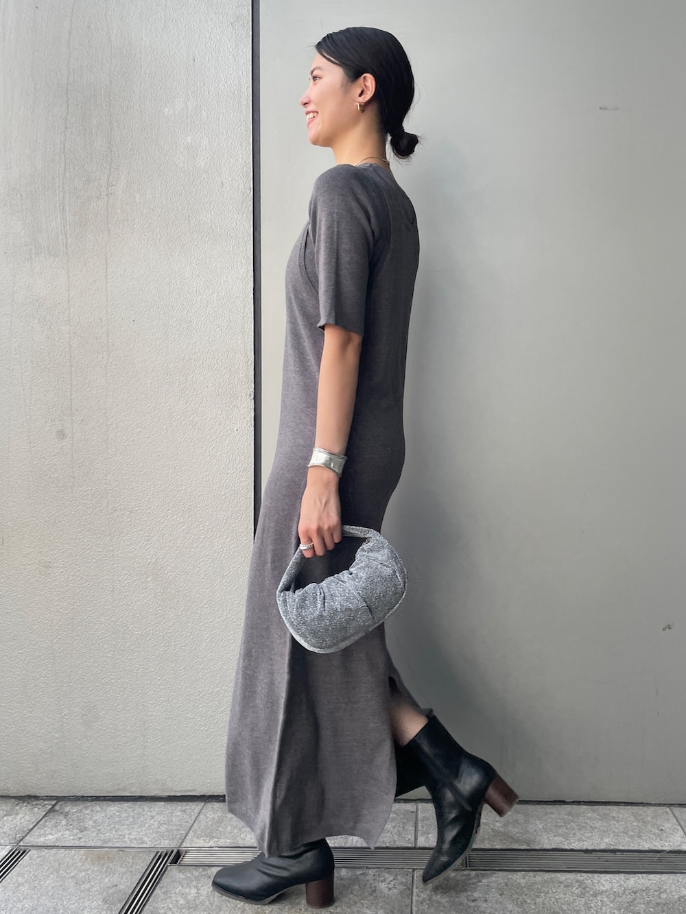 グレー系のワンピース、ブラック系のブーツ、ホワイト系のハンドバッグを着用したレディースの秋コーディネートの3枚目の写真