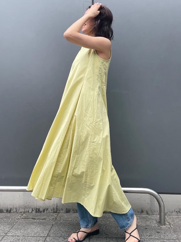 ホワイト系のハンドバッグ、ブルー系のデニムパンツ、グリーン系のワンピースを着用したレディースの春コーディネートの3枚目の写真