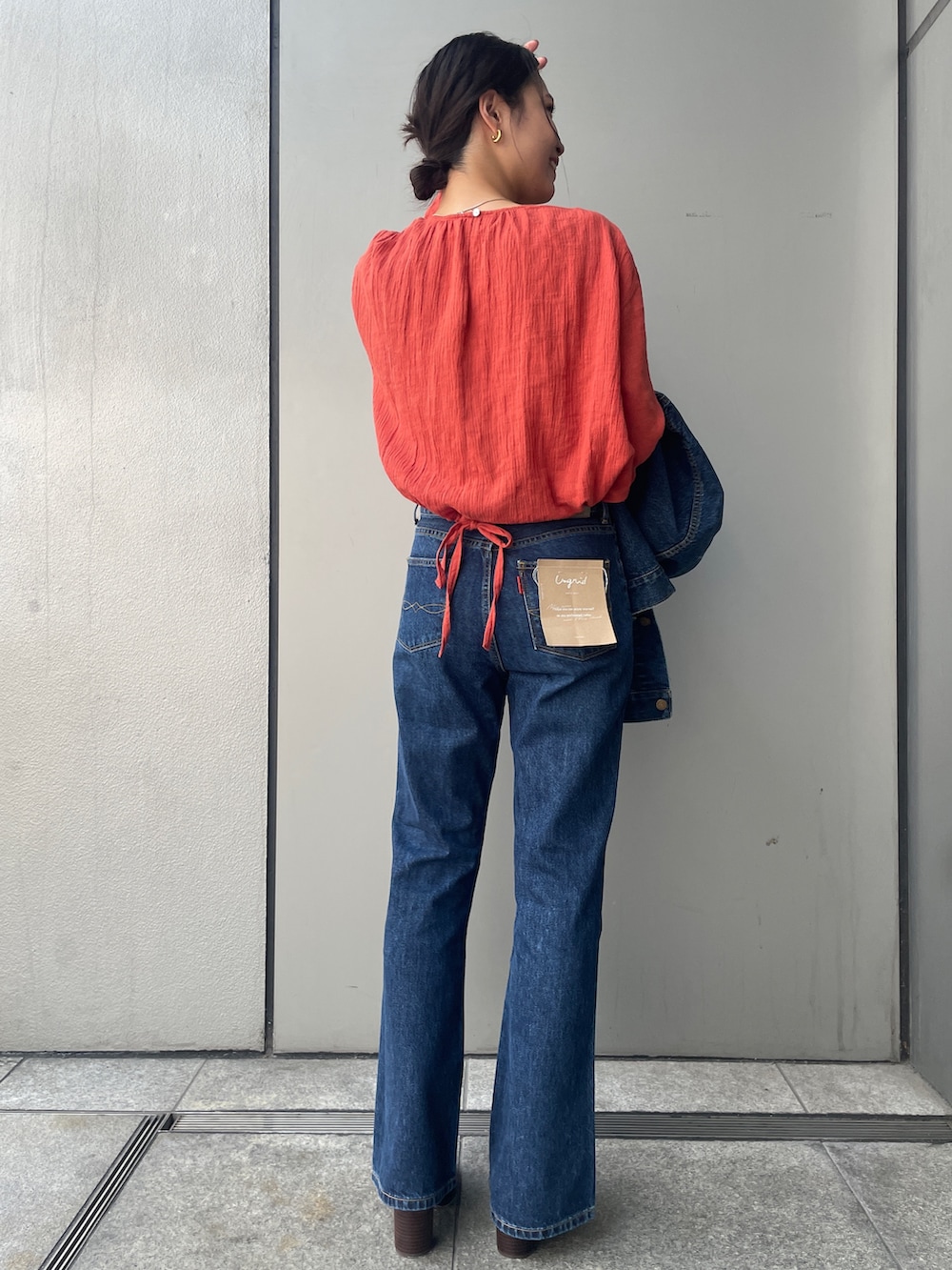 ブルー系のデニムパンツ、オレンジ系のシャツ/ブラウス、ブルー系のデニムジャケットを着用したレディースの夏コーディネートの3枚目の写真