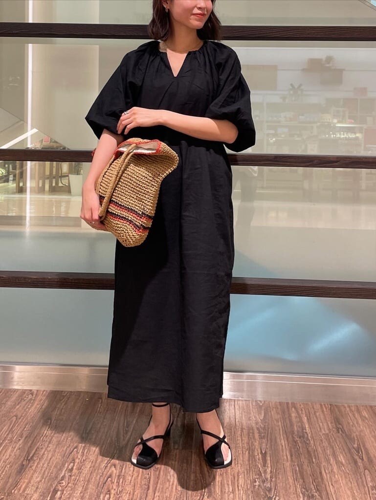 ブラック系のワンピース、ブラック系のサンダル、ベージュ系のトートバッグを着用したレディースの春コーディネートの2枚目の写真