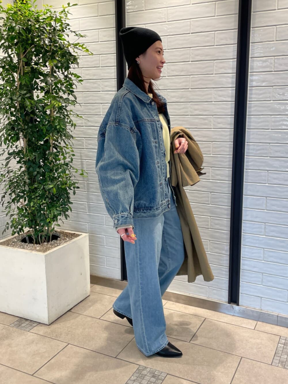 ブルー系のデニムパンツ、ブルー系のデニムジャケット、イエロー系のニット/セーターを着用したレディースの冬コーディネートの2枚目の写真