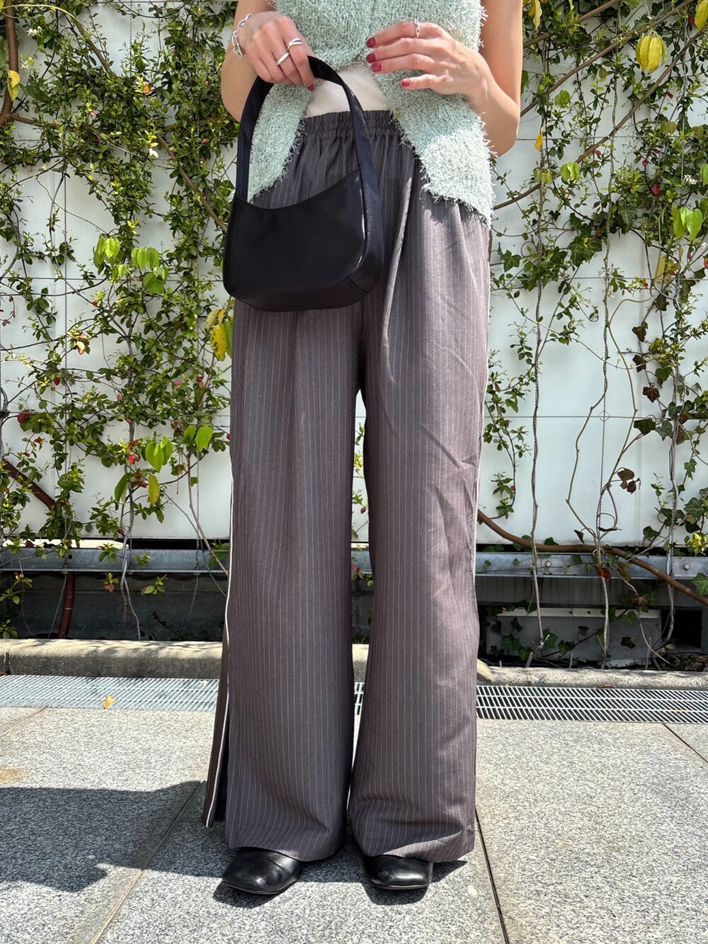 グリーン系のベスト、グレー系のその他パンツ、ブラック系のハンドバッグを着用したレディースの春コーディネートの4枚目の写真