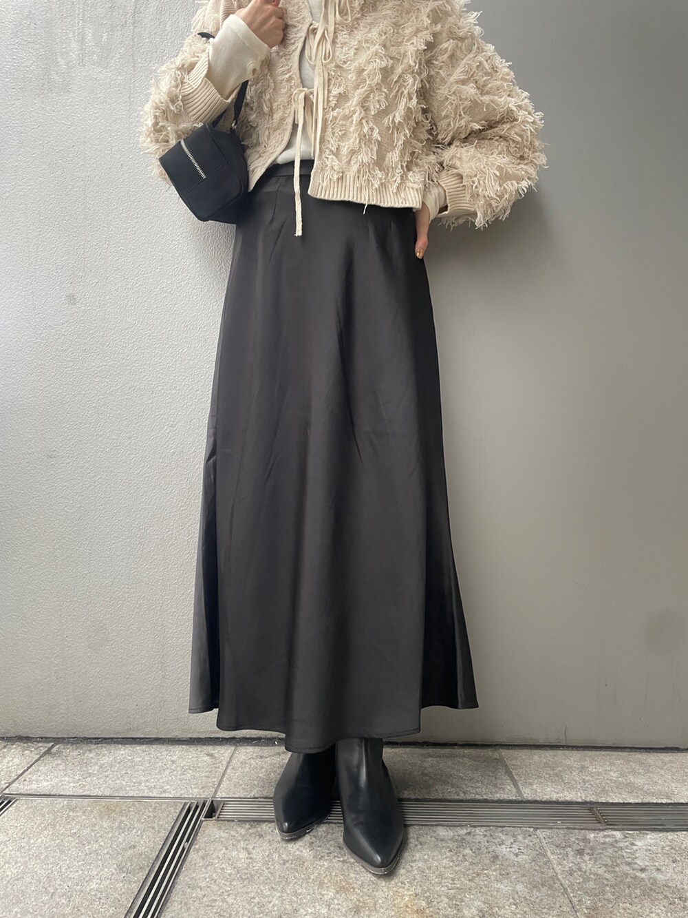 ホワイト系のニット/セーター、ブラック系のスカート、ブラック系のブーツを着用したレディースの秋コーディネートの4枚目の写真