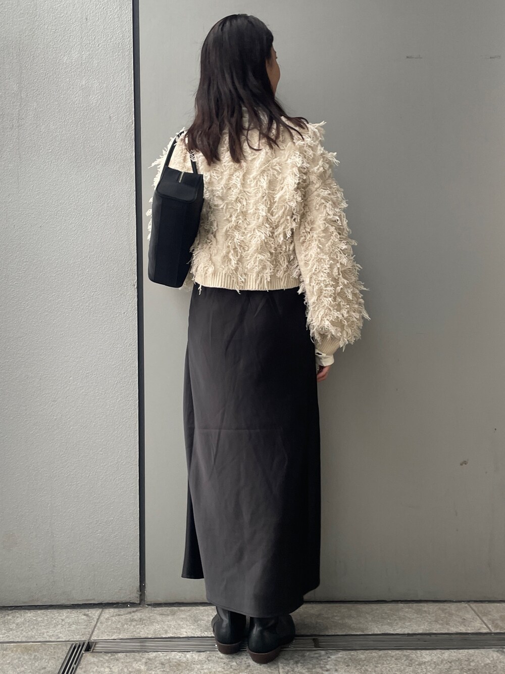 ホワイト系のニット/セーター、ブラック系のスカート、ブラック系のブーツを着用したレディースの秋コーディネートの3枚目の写真