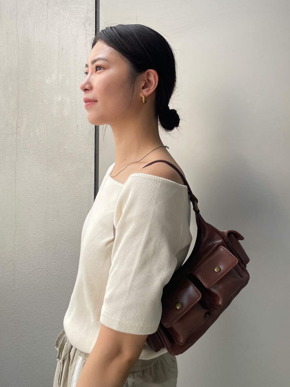 ベージュ系のスカート、ホワイト系のTシャツ/カットソー、ブラウン系のブーツを着用したレディースの夏コーディネートの6枚目の写真