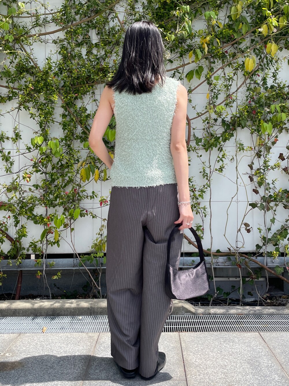 グリーン系のベスト、グレー系のその他パンツ、ブラック系のハンドバッグを着用したレディースの春コーディネートの3枚目の写真
