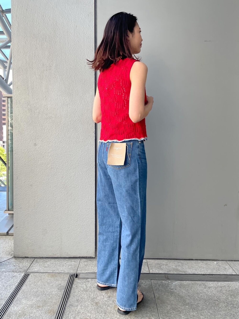 レッド系のニット/セーター、ブルー系のデニムパンツ、ホワイト系のキャミソールを着用したレディースの春コーディネートの2枚目の写真