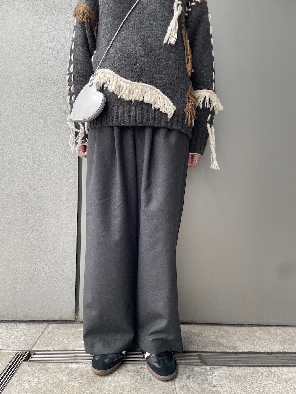 グレー系のニット/セーター、ホワイト系のTシャツ/カットソー、グレー系のその他パンツを着用したレディースの冬コーディネートの4枚目の写真