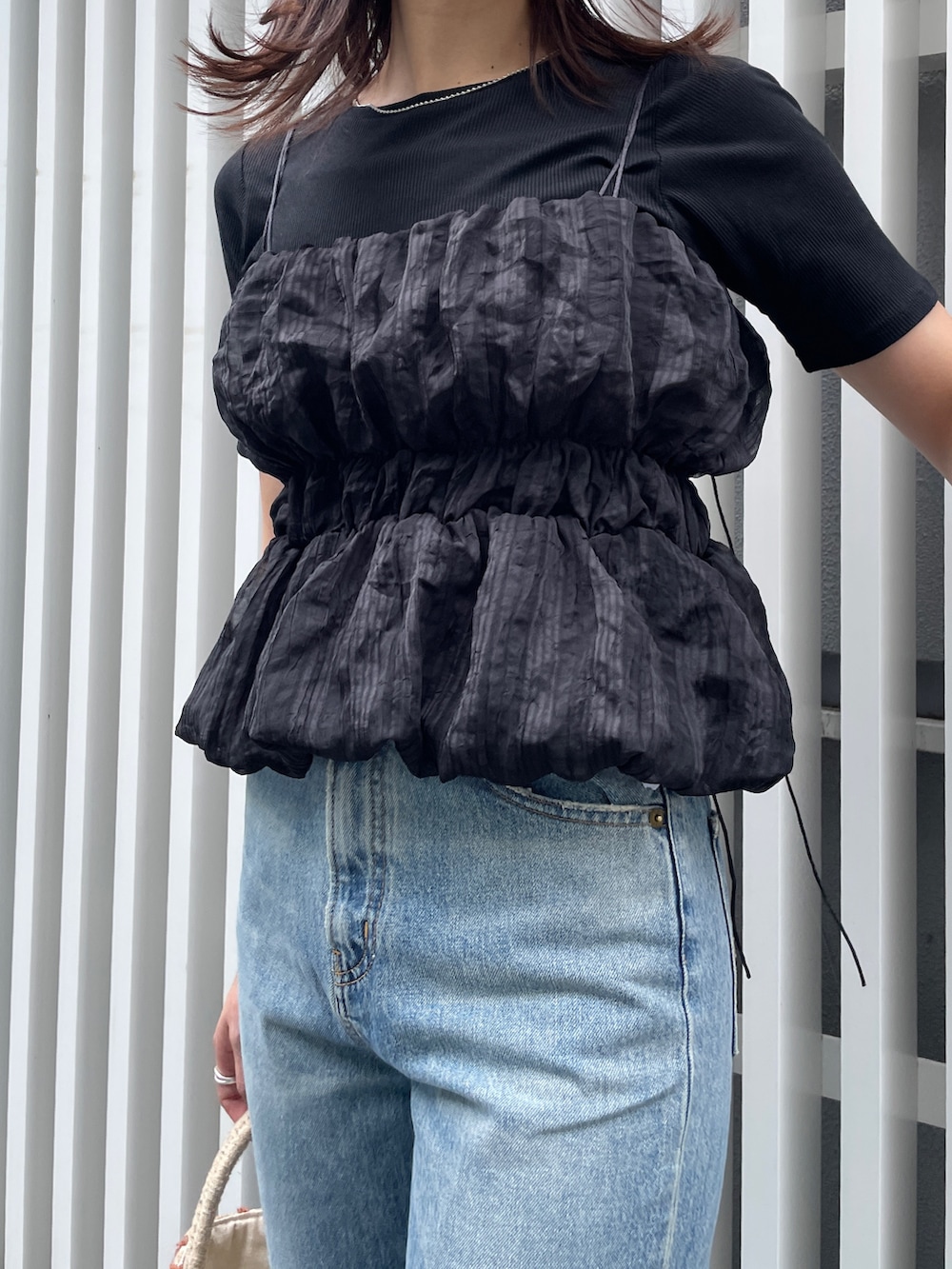 ブルー系のデニムパンツ、ブラック系のTシャツ/カットソー、ベージュ系のハンドバッグを着用したレディースの夏コーディネートの4枚目の写真