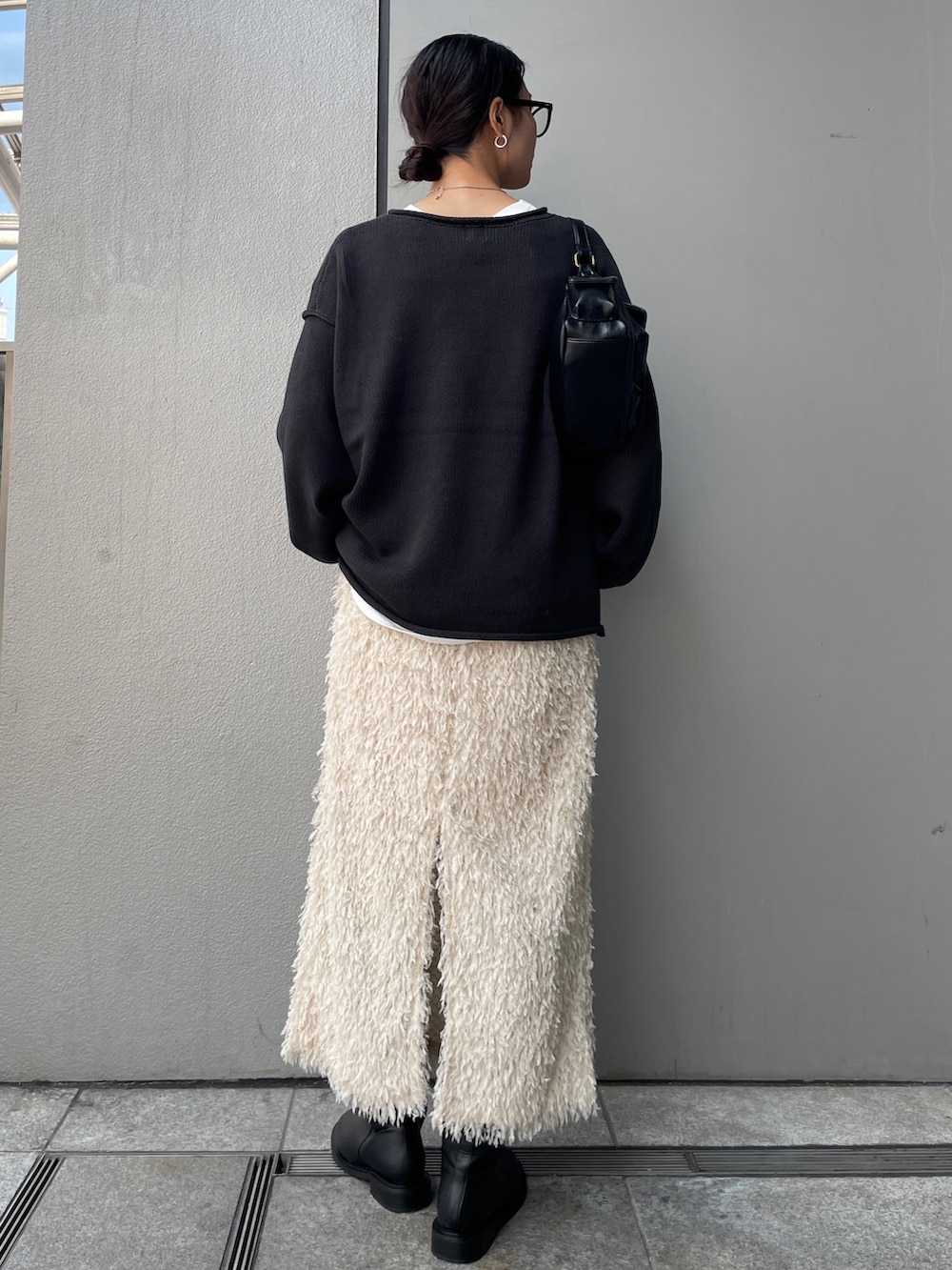 グレー系のニット/セーター、ホワイト系のTシャツ/カットソー、ホワイト系のスカートを着用したレディースの秋コーディネートの2枚目の写真