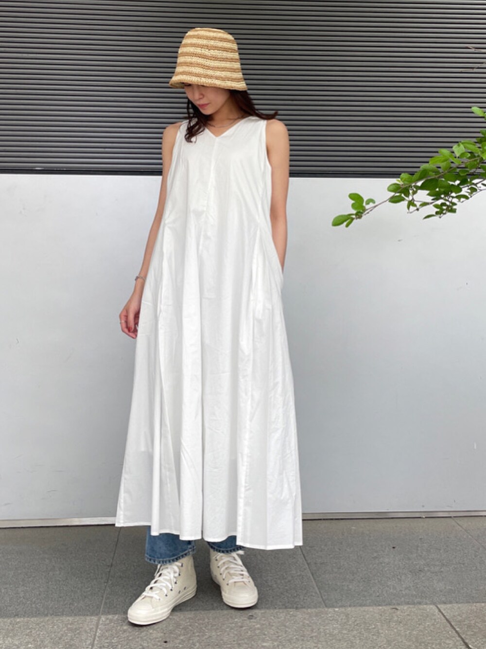 ホワイト系のワンピース、ブルー系のデニムパンツ、ホワイト系のスニーカーを着用したレディースの春コーディネートの2枚目の写真