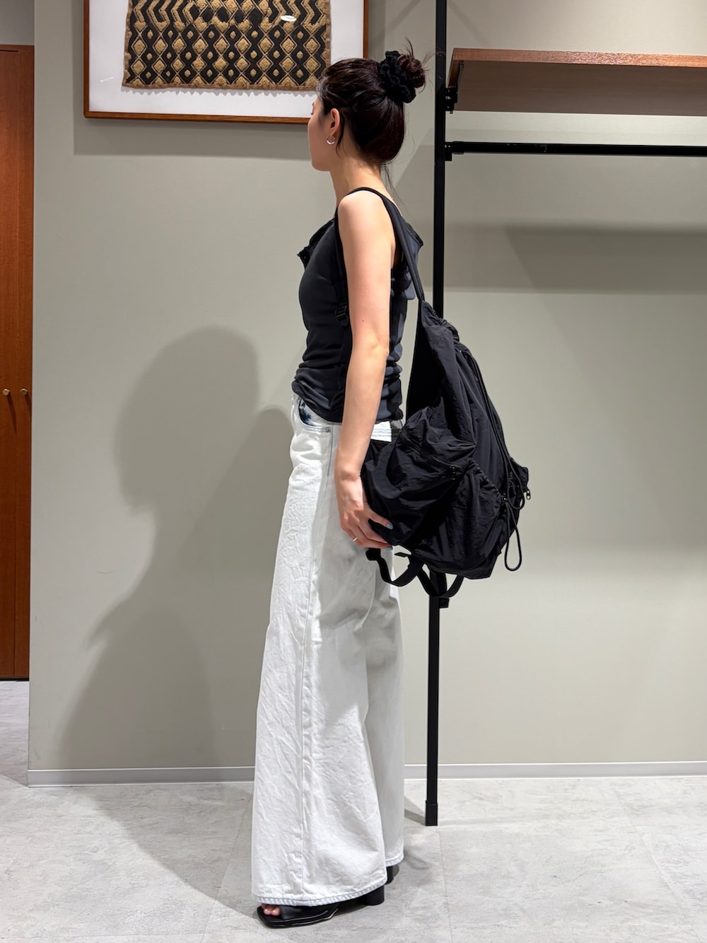 ホワイト系のデニムパンツ、ブラック系のサンダル、グレー系のタンクトップを着用したレディースの夏コーディネートの2枚目の写真