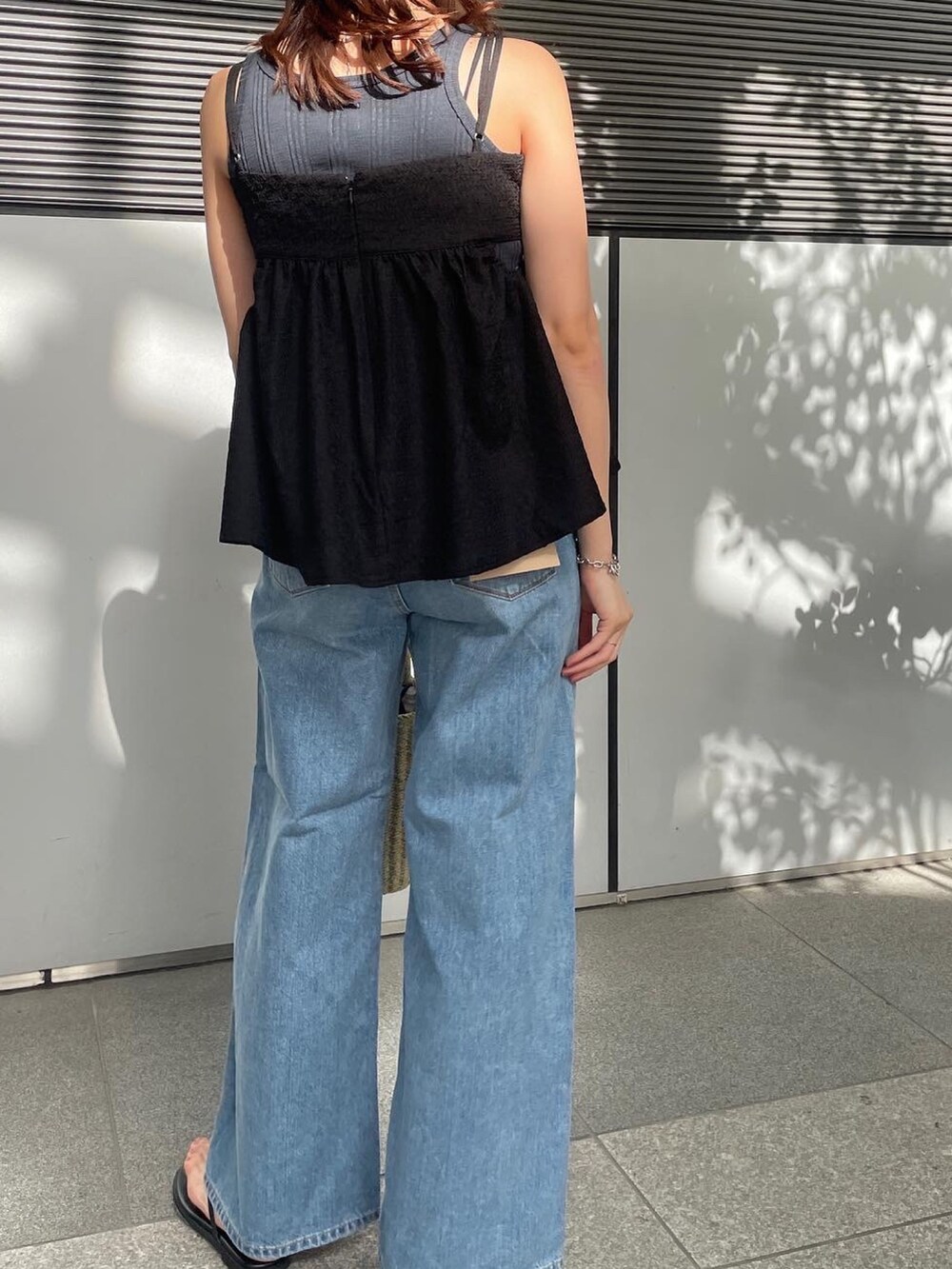 ブルー系のデニムパンツ、ブラック系のシャツ/ブラウス、ブラック系のサンダルを着用したレディースの春コーディネートの2枚目の写真