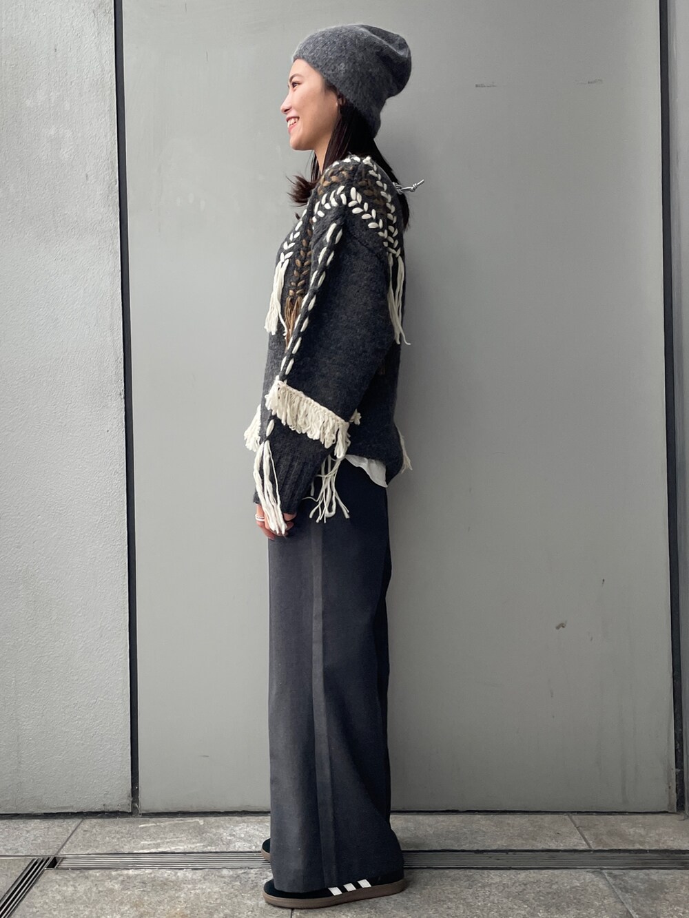 グレー系のニット/セーター、ホワイト系のTシャツ/カットソー、グレー系のその他パンツを着用したレディースの冬コーディネートの2枚目の写真