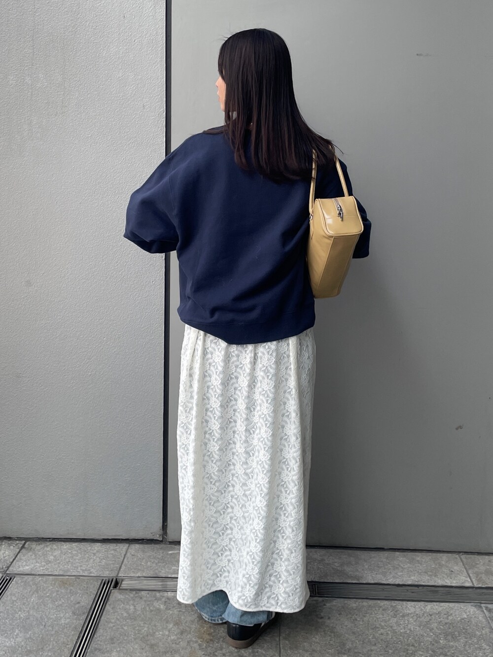 ホワイト系のワンピース、ブルー系のデニムパンツ、ベージュ系のハンドバッグを着用したレディースの冬コーディネートの2枚目の写真