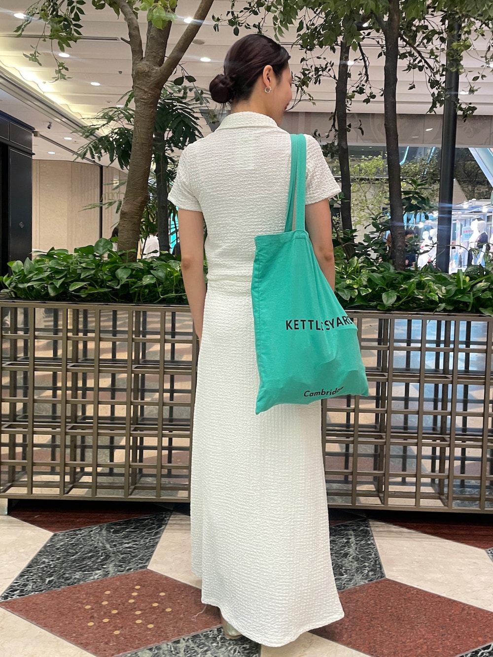 ホワイト系のスカート、ホワイト系のポロシャツ、ゴールド系のバレエシューズを着用したレディースの夏コーディネートの3枚目の写真