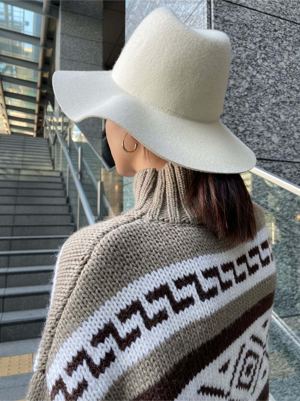 ブルー系のデニムパンツ、ベージュ系のニット/セーター、ホワイト系のハットを着用したレディースの秋コーディネートの3枚目の写真