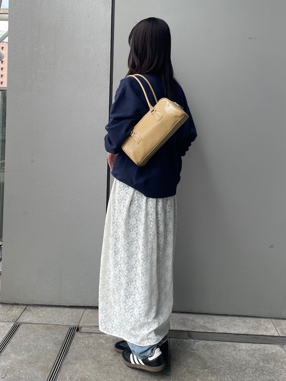 ホワイト系のワンピース、ブルー系のデニムパンツ、ベージュ系のハンドバッグを着用したレディースの冬コーディネートの3枚目の写真