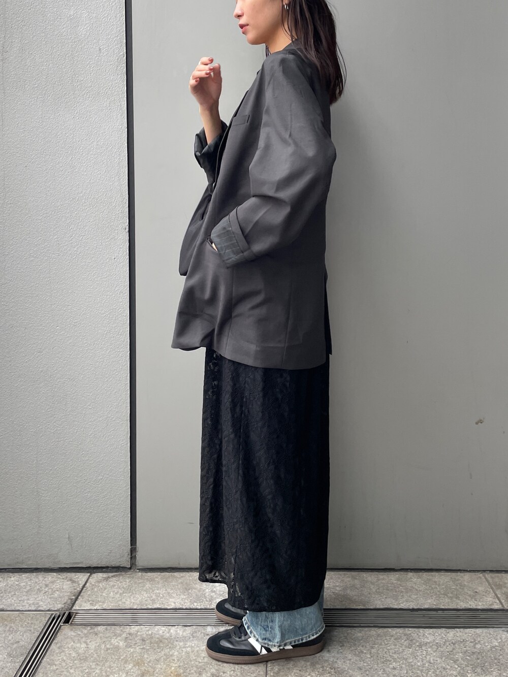 グレー系のテーラードジャケット、ブラック系のワンピース、ブルー系のデニムパンツを着用したレディースの秋コーディネートの3枚目の写真