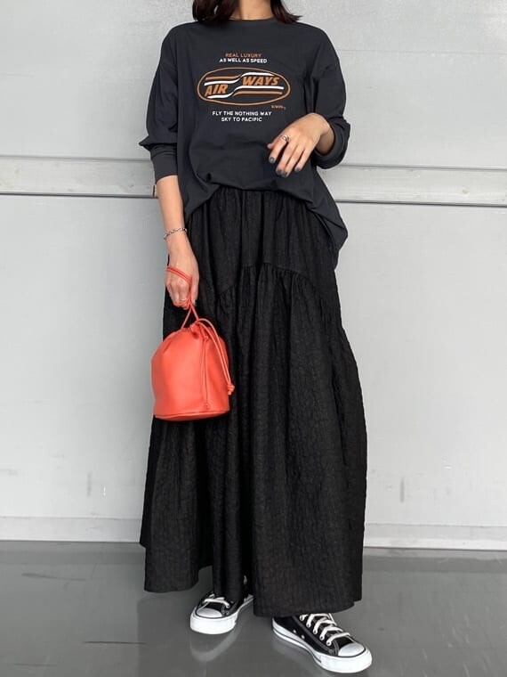 ブラック系のスカート、オレンジ系のハンドバッグ、グレー系のTシャツ/カットソーを着用したレディースの夏コーディネートの2枚目の写真