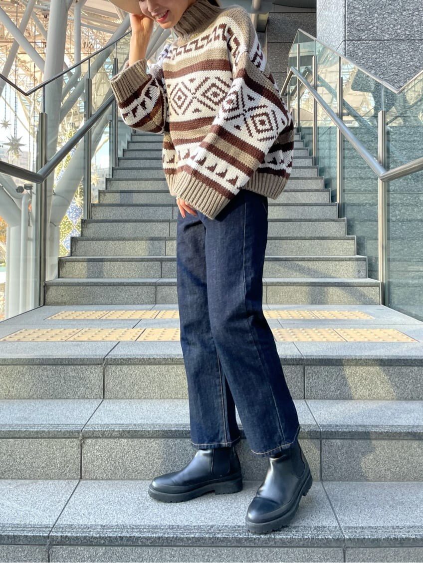 ブルー系のデニムパンツ、ベージュ系のニット/セーター、ホワイト系のハットを着用したレディースの秋コーディネートの2枚目の写真