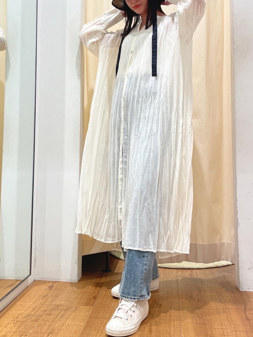 ホワイト系のワンピース、ブルー系のデニムパンツ、ホワイト系のスニーカーを着用したレディースの春コーディネートの3枚目の写真