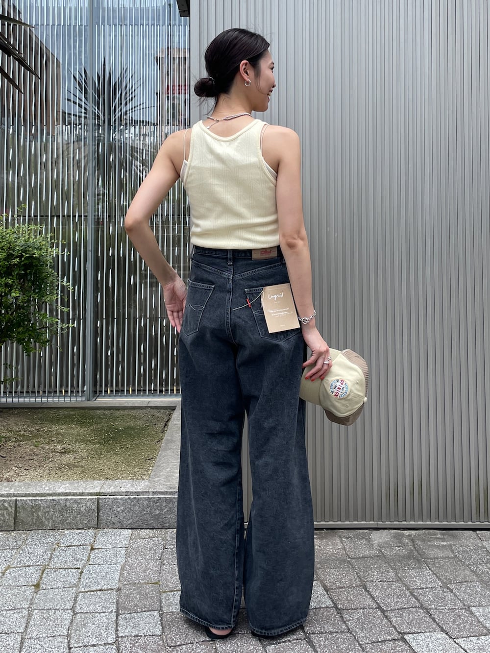 イエロー系のタンクトップ、ブラック系のデニムパンツ、ブラック系のサンダルを着用したレディースの夏コーディネートの3枚目の写真