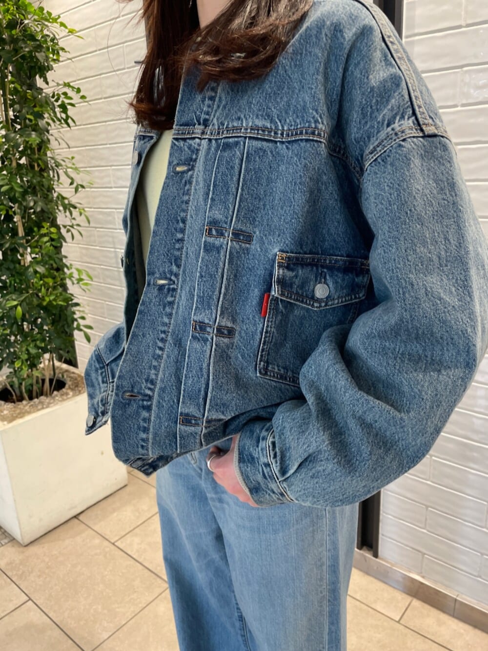 ブルー系のデニムパンツ、ブルー系のデニムジャケット、イエロー系のニット/セーターを着用したレディースの冬コーディネートの4枚目の写真