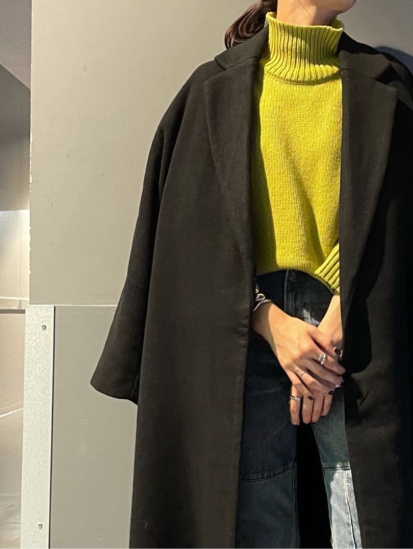 ブラック系のチェスターコート、ブルー系のデニムパンツ、グリーン系のニット/セーターを着用したレディースの秋コーディネートの2枚目の写真