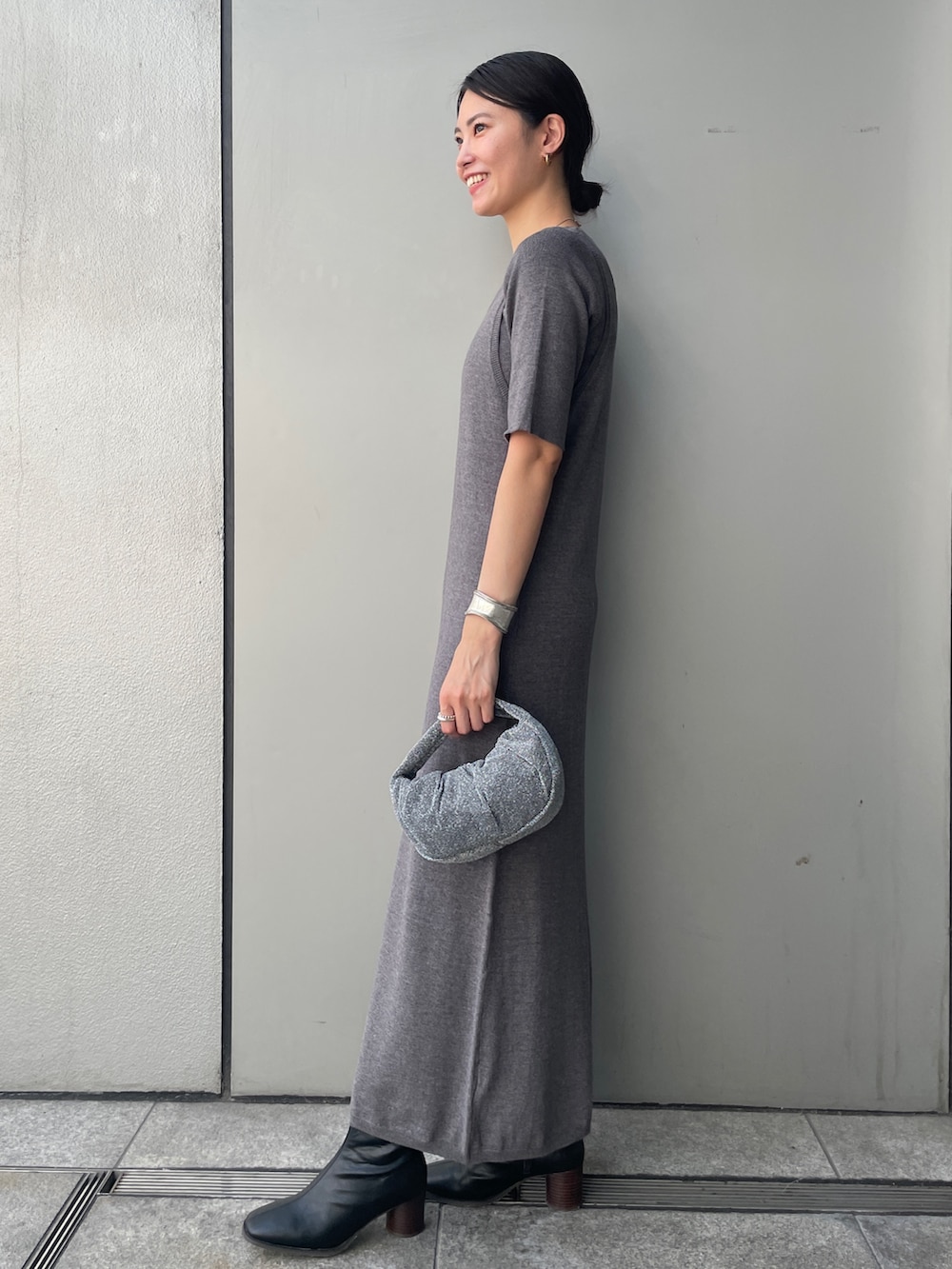 グレー系のワンピース、ブラック系のブーツ、ホワイト系のハンドバッグを着用したレディースの秋コーディネートの2枚目の写真