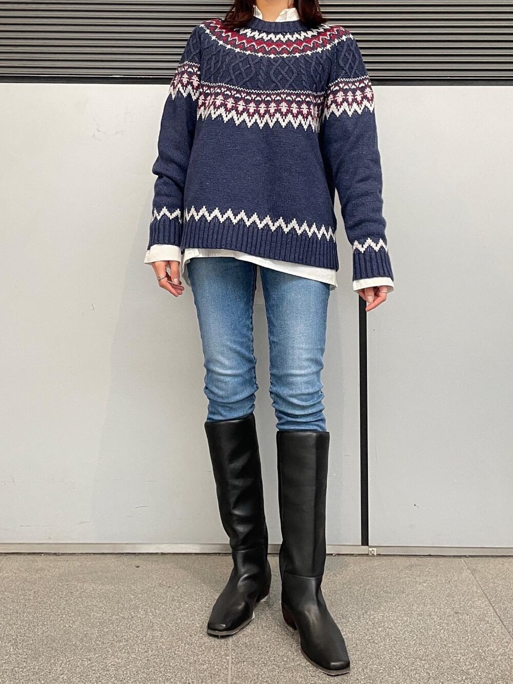 ブルー系のニット/セーター、ホワイト系のシャツ/ブラウス、ブルー系のデニムパンツを着用したレディースの秋コーディネートの2枚目の写真