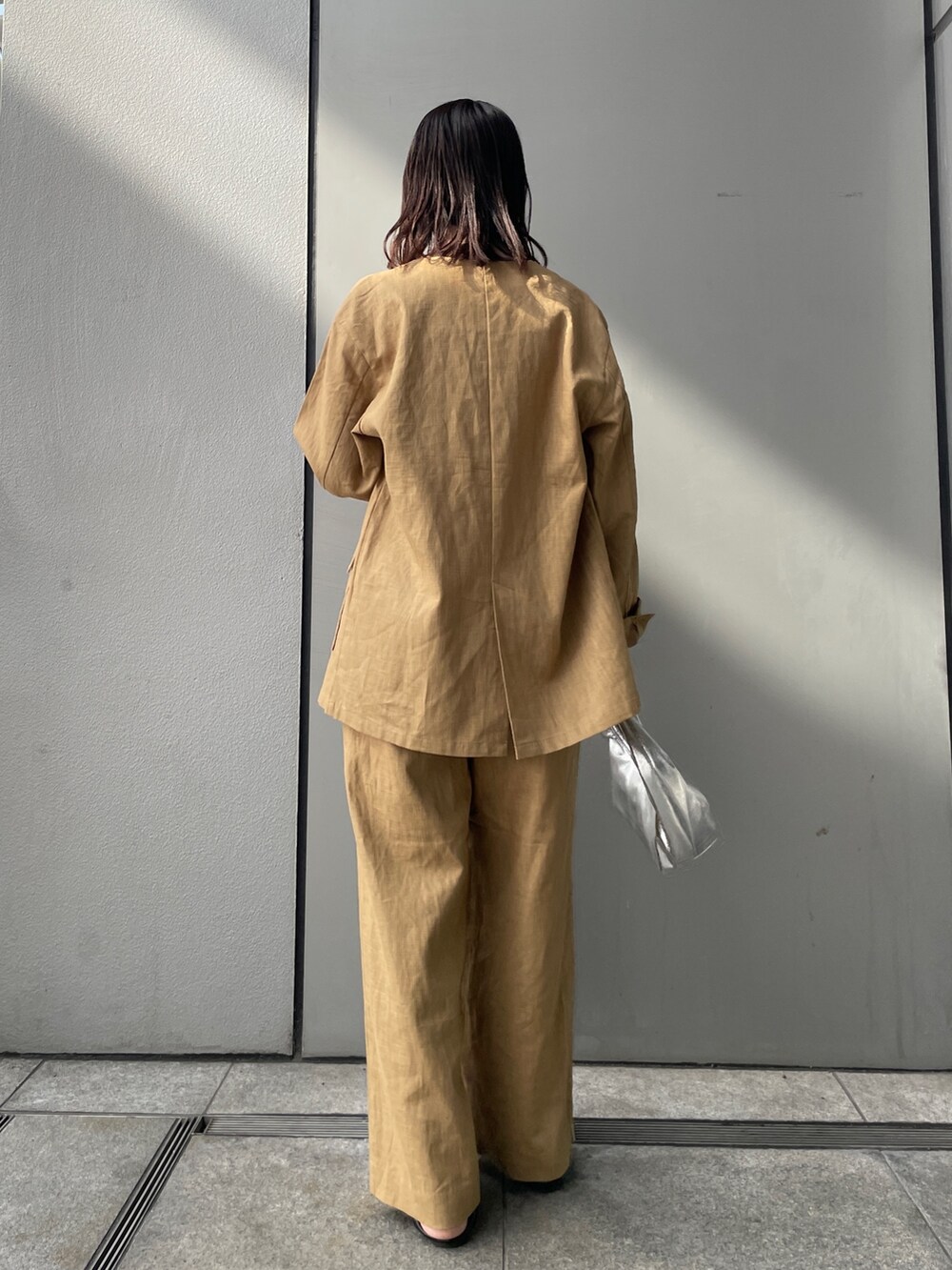 ベージュ系のテーラードジャケット、ベージュ系のその他パンツ、ホワイト系のキャミソールを着用したレディースの春コーディネートの2枚目の写真