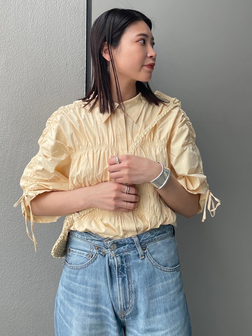 ブルー系のデニムパンツ、イエロー系のシャツ/ブラウス、ベージュ系のショルダーバッグを着用したレディースの春コーディネートの5枚目の写真