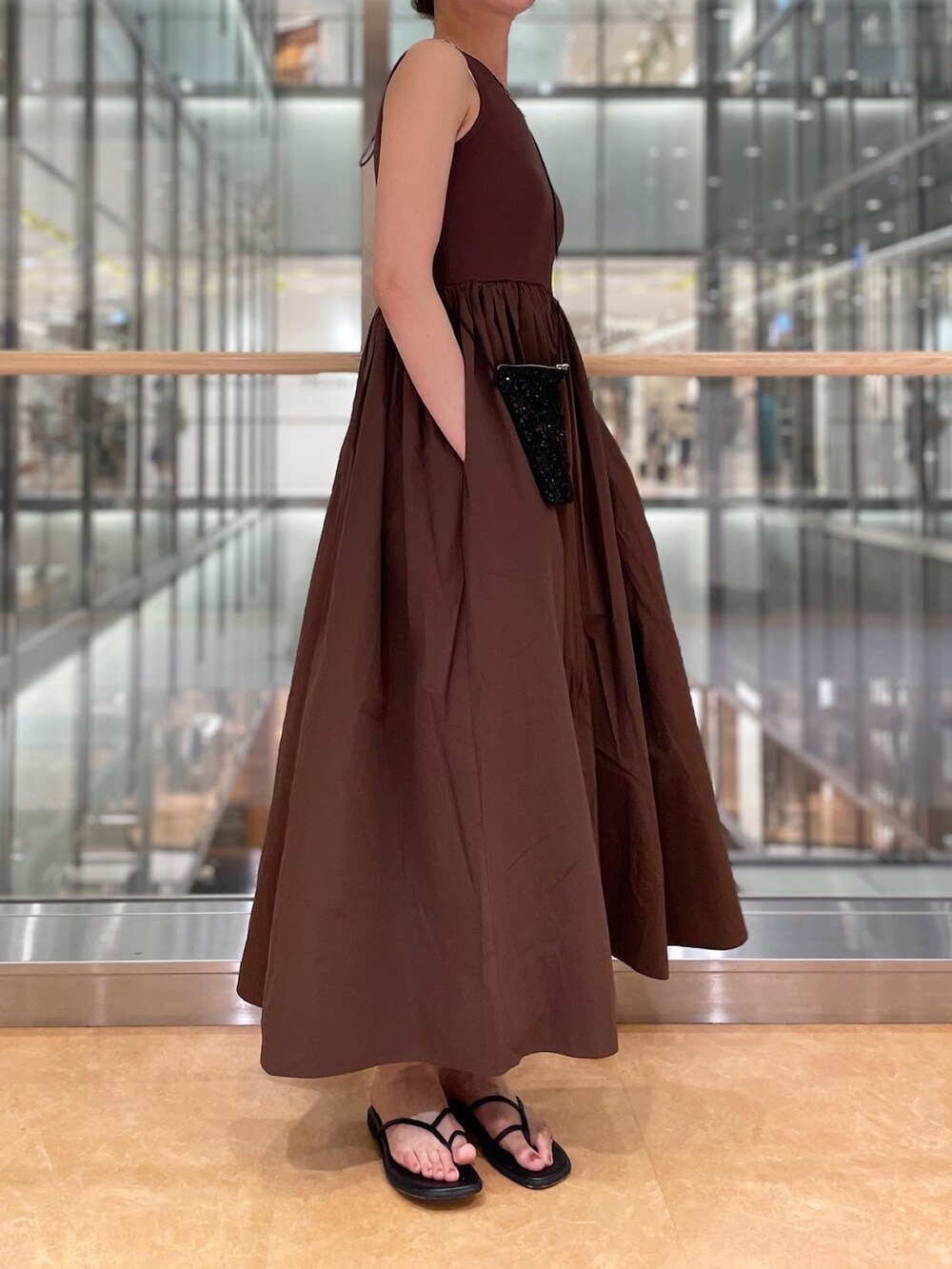 ブラウン系のワンピース、ブラック系のショルダーバッグ、ブラック系のサンダルを着用したレディースの春コーディネートの3枚目の写真