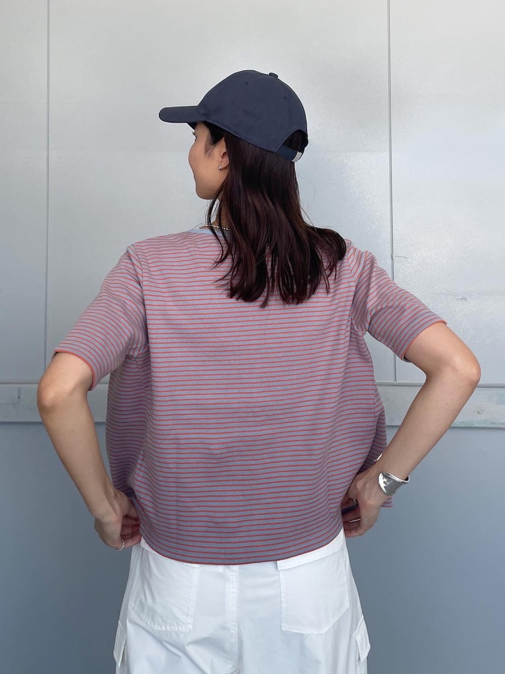 ホワイト系のその他パンツ、オレンジ系のキャミソール、ブルー系のキャップを着用したレディースの夏コーディネートの3枚目の写真