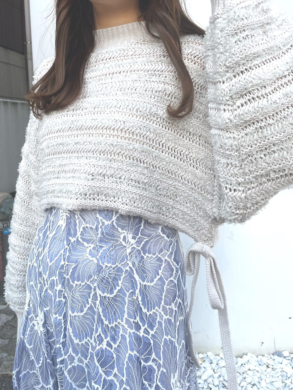 グレー系のニット/セーター、ブルー系のスカート、ホワイト系のハンドバッグを着用したレディースの冬コーディネートの3枚目の写真