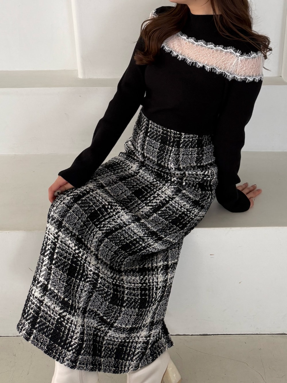 ブラック系のニット/セーター、ブラック系のスカート、ホワイト系のブーツを着用したレディースの秋コーディネートの5枚目の写真